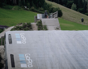 Ein Biker führt einen Trick über dem GoPro Bagjump-Luftkissen in Leogang aus. Der weiche Landeplatz dient zur sicheren Übung von Sprüngen und Tricks. | © Yvonne Hörl