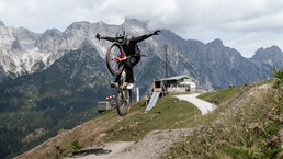 Mountainbiker:innen springt auf einem Trail im EPIC Bikepark Leogang vor beeindruckender Alpenkulisse. | © Yvonne Hörl