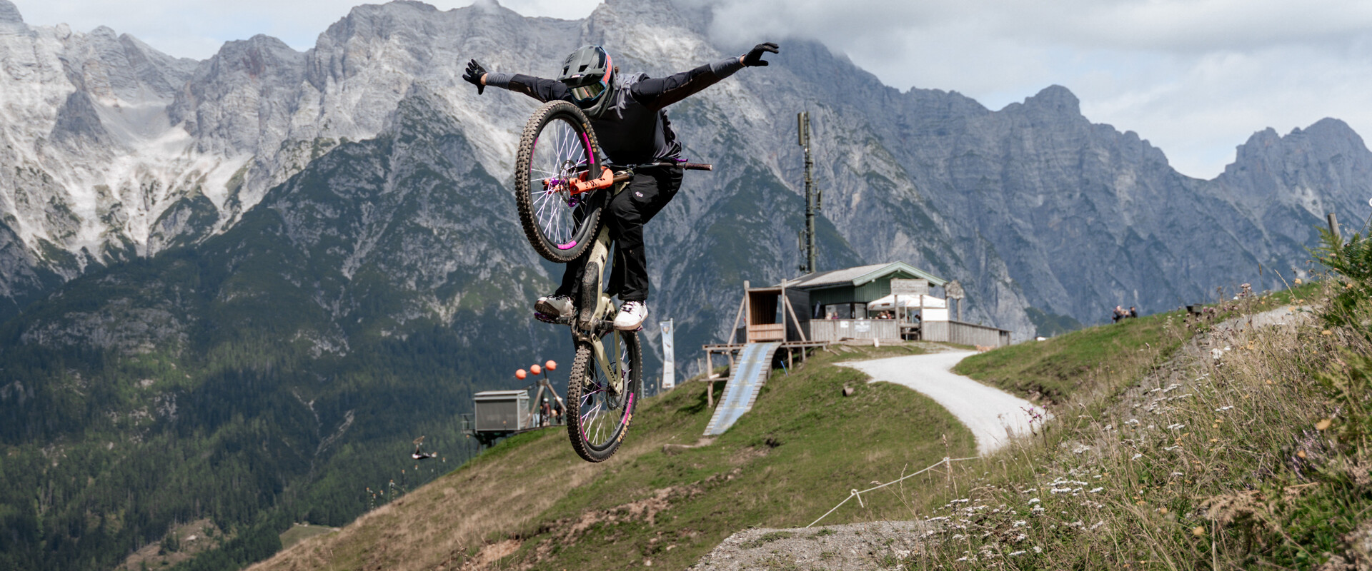 Mountainbiker:innen springt auf einem Trail im EPIC Bikepark Leogang vor beeindruckender Alpenkulisse. | © Yvonne Hörl